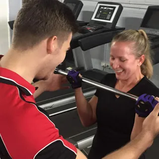 women weight training doing barbell straight curls in a gym