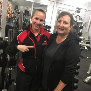 Female Brisbane Personal Trainer smiling and pointing to her client after she finished her session.